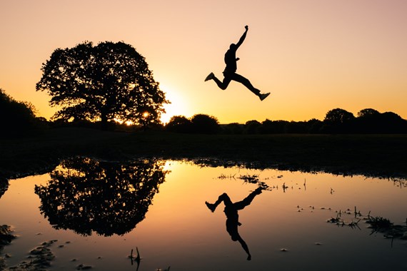 Individual jumping over lake